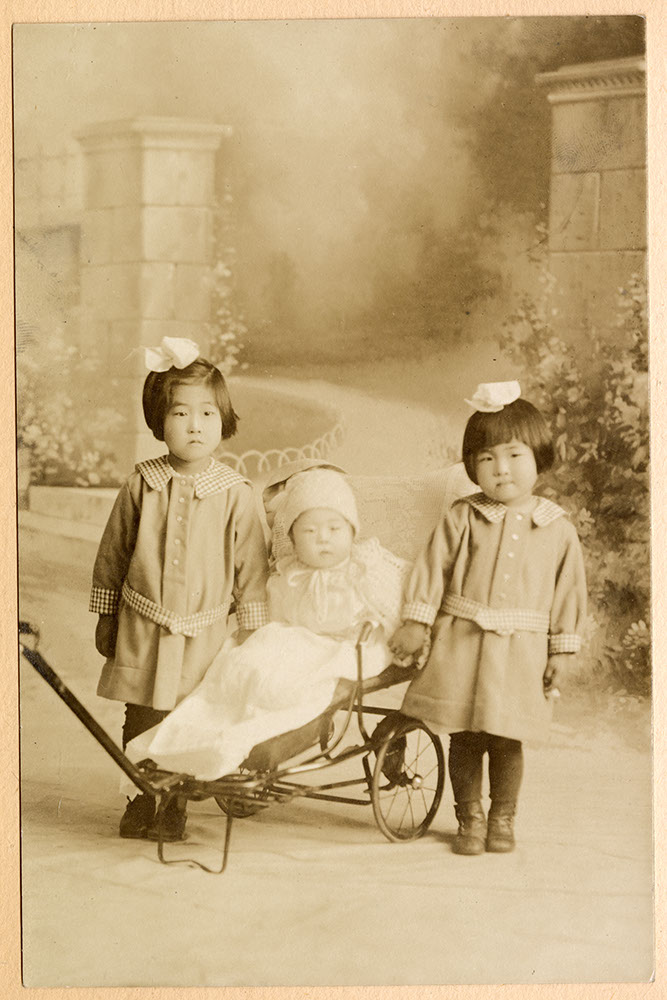 Formal portrait of two little girls and a baby in a stroller